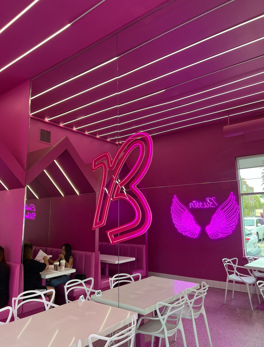 Bussin cafe interior pink neon B and wing signs — commercial neon Calgary
